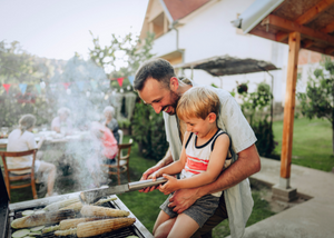 Father helping son cooking on the BBQ in their AVJennings Arbor Townhome, located in Rochedale, QLD, 4123. Townhomes for sale in Rochedale. 