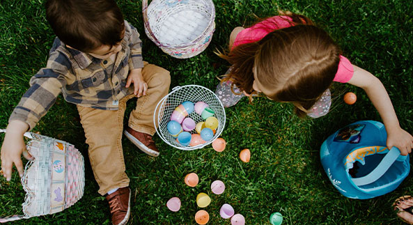 Children sitting on grass playing with easter eggs in their Aspect backyard by AVJennings located in Mernda VIC 3754. Land for sale Mernda. 