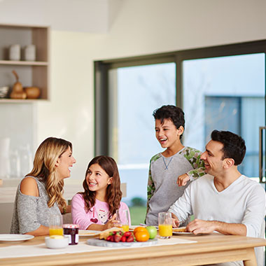 Family sitting around breakfast table and laughing in their Lyndarum North townhome located in Wollert VIC 3750. Land for sale in Wollert, townhomes for sale in Wollert. 